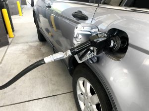 Silver car with gas being pumped into tank at a gas station